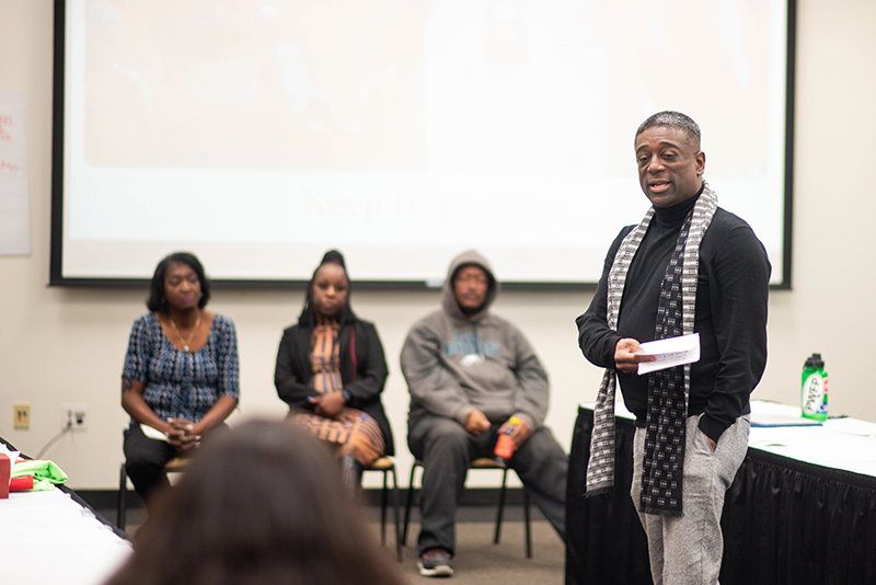 A seminar leader stands at the front of the room, guiding participants through a workshop session.