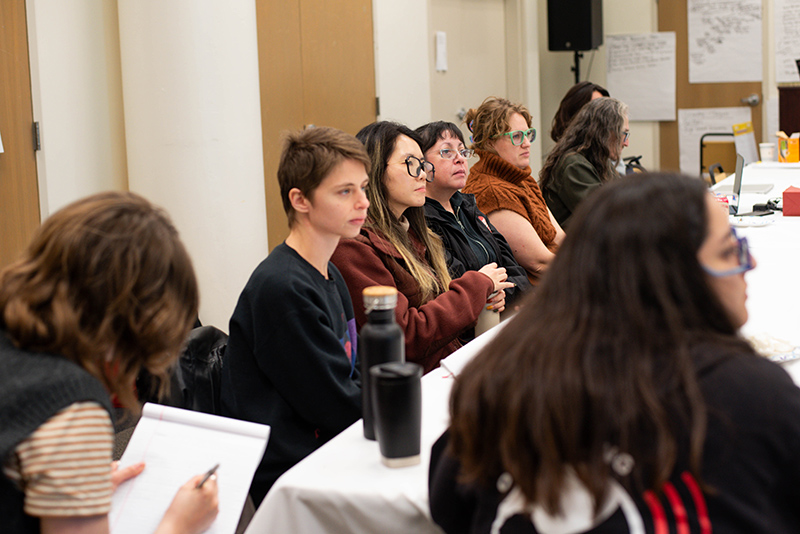 Fellows sit together, fully focused on a speaker sharing insights at a convening.